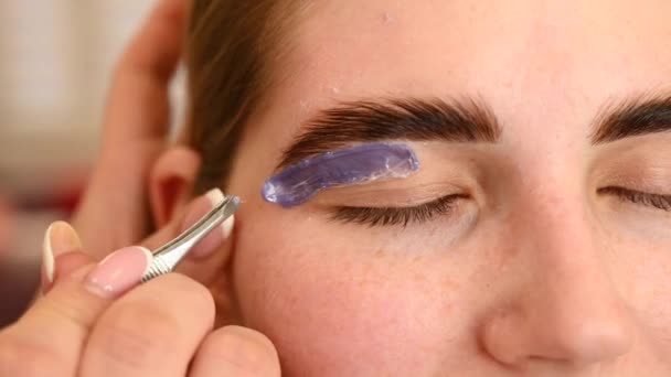 Eyebrow correction. The master removes excess hairs with wax and tweezers. — Stock Video