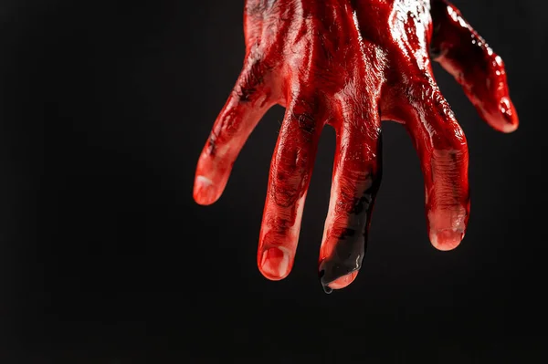 Primer plano de una mano masculina manchada de sangre sobre un fondo negro. — Foto de Stock