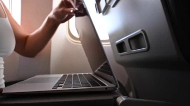 Maskeli meçhul kadın uçuş sırasında pencerenin yanında otururken dizüstü bilgisayarda çalışıyor. Serbest Çalışan Bir Yolculuk.