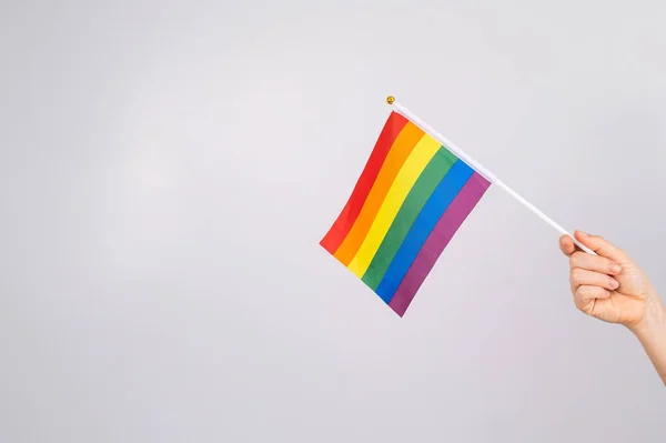 Uma mulher está segurando uma bandeira do arco-íris em um fundo branco. — Fotografia de Stock