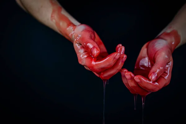 Mãos das mulheres em um líquido vermelho viscoso semelhante ao sangue. — Fotografia de Stock