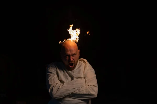 Hombre calvo en una camisa de fuerza con la cabeza ardiendo sobre un fondo oscuro. — Foto de Stock