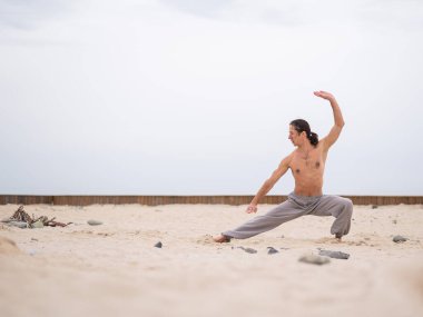 Kafkasyalı, uzun saçlı, dışarıda qigong antrenmanı yapan bir adam.. 