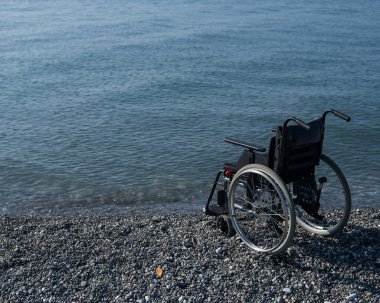 Kayalık bir sahilde boş bir tekerlekli sandalye..