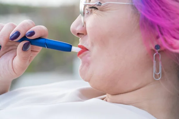 Mujer caucásica con el pelo de color fuma un cigarrillo electrónico. — Foto de Stock