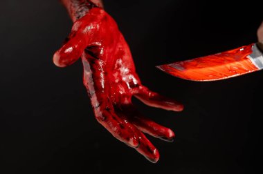 Siyah arka planda kanlı eli olan bir adam bıçak tutuyor.. 