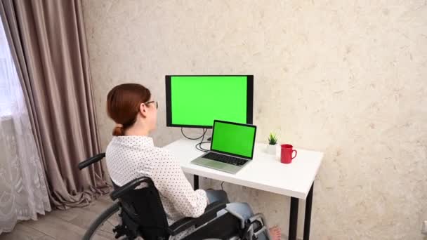 Caucasian woman in a wheelchair talking on a video link. Green screen on laptop. — Stock Video