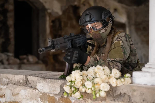 Blanke vrouw in militair uniform met een machinegeweer en een boeket witte rozen. — Stockfoto
