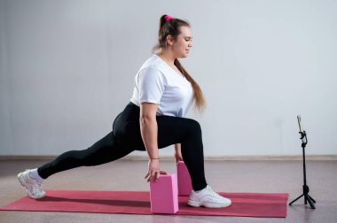 Genç Artı Boyutlu Kadın İnternet 'te esniyor. Esnek kız yoga yapıyor ve internetten dizüstü bilgisayarda ders izliyor.