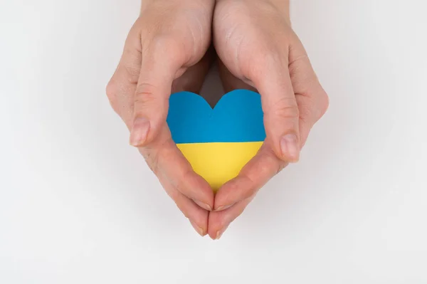 Beyaz arka planda Ukrayna bayrağı taşıyan bir kalp taşıyan bir kadın.. — Stok fotoğraf