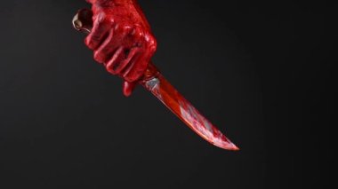 Siyah arka planda kanlı eli olan bir adam bıçak tutuyor.. 