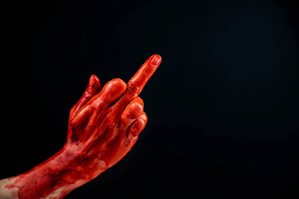 Mano femenina manchada con sangre muestra el dedo medio sobre un fondo negro. — Foto de Stock
