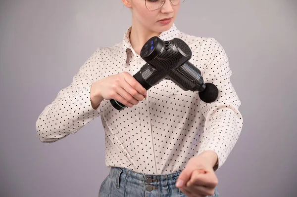 Kaukasische Geschäftsfrau massiert ihren Bizeps mit einem Percussion-Massagegerät. — Stockfoto