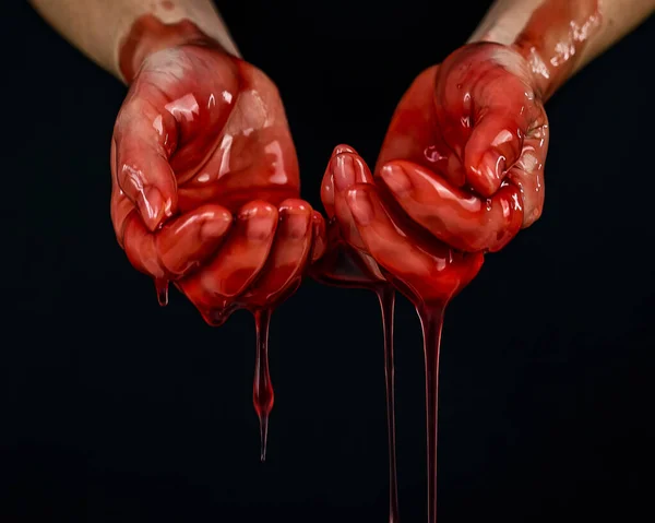 Les mains des femmes dans un liquide rouge visqueux similaire au sang. — Photo