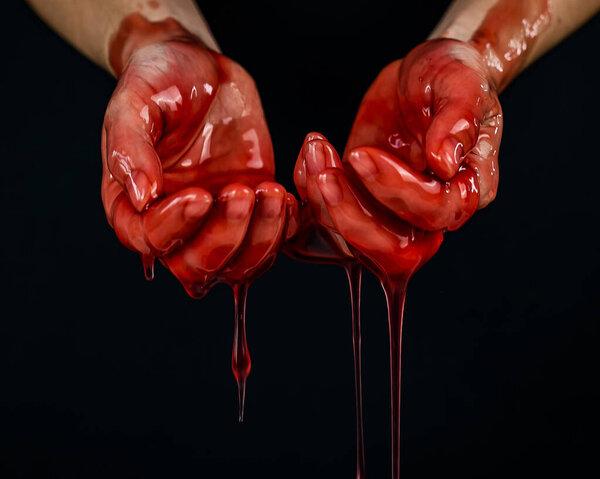 Womens hands in a viscous red liquid similar to blood.