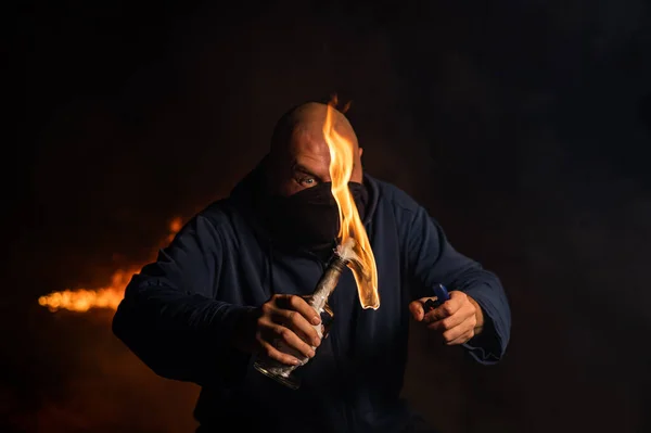 Maskeli bir adam yanan bir şişe tutuyor. Molotof kokteyli. — Stok fotoğraf