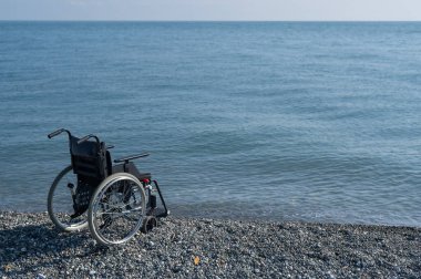 Kayalık bir sahilde boş bir tekerlekli sandalye..