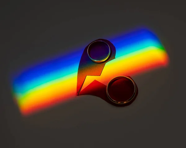 Rainbow beam on wedding rings with a broken heart. lgbt flag.