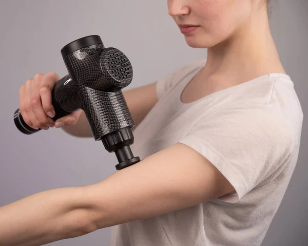 白人妇女用一把按摩枪治疗手臂肌肉疼痛. — 图库照片