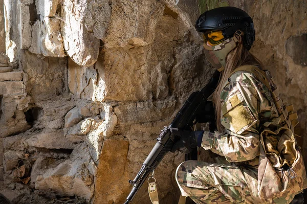 Retrato de una mujer con casco y gafas con una ametralladora en las manos. Una soldado con uniforme de camuflaje sostiene un arma. —  Fotos de Stock