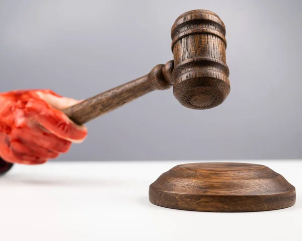 Female judge with bloody hands beats the gavel on a white background. — Stock Photo, Image