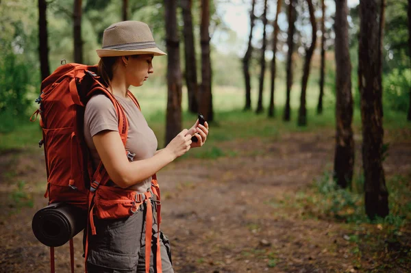 Young caucasian woman is hiking and using a compass in the forest. — Stock Photo, Image