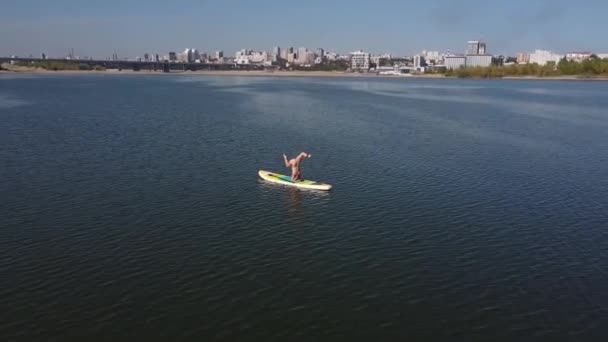 Vista dall'alto. Donna caucasica che fa esercizi di fitness su una tavola da paddle. — Video Stock