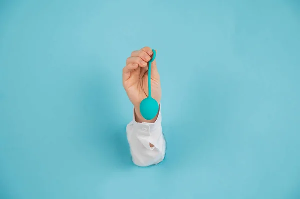 Bir kadın elini mavi arka planda bir delikten çıkarır ve vajina yumurtası tutar.. — Stok fotoğraf