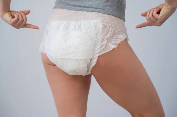 Vista trasera de una mujer señalando pañales para adultos. Problema de incontinencia. —  Fotos de Stock