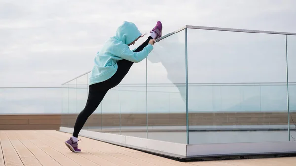 Mujer caucásica en una sudadera se extiende en la cuerda al aire libre. —  Fotos de Stock