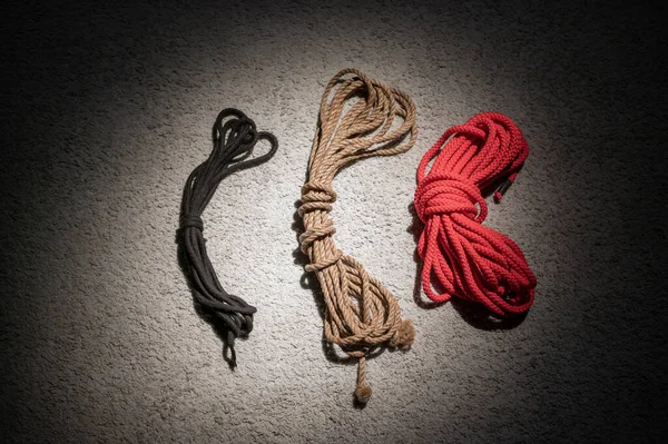 Espinho de corda para jogos de interpretação de papéis em um sofá de couro vermelho. Conceito BDSM. Um laço para a arte japonesa de shibari. Não há pessoas . — Fotografia de Stock