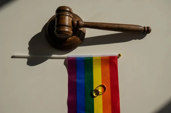 Legalización de matrimonios entre personas del mismo sexo. Arco iris bandera anillos de boda y jueces martillo. —  Fotos de Stock