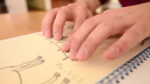 Ein sehbehinderter Mann berührt eine dreidimensionale Illustration in einem Buch in Brailleschrift. — Stockvideo