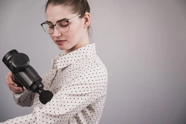 Kaukasische Geschäftsfrau massiert ihren Bizeps mit einem Percussion-Massagegerät. — Stockfoto