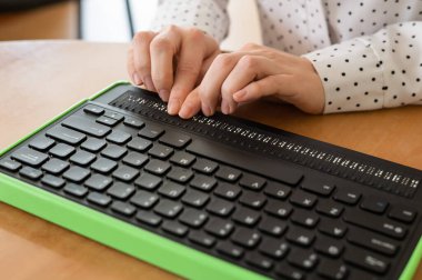 Kör bir kadın Braille ekranı ve klavyesi olan bir bilgisayar kullanıyor. Özel aygıt.