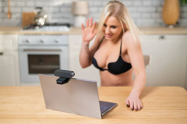 Девушка в нижнем белье флиртует с веб-камерой на ноутбуке. Женщина работает в секс-индустрии онлайн — стоковое фото