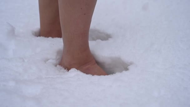 Primer plano de una mujer caminando descalza en la nieve. Aumentar la inmunidad con crioterapia. — Vídeo de stock