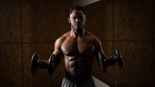 Izmos, sötét bőrű férfi súlyzókkal gyakorol.. — Stock Fotó