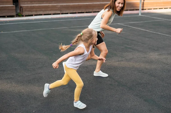 Donna caucasica entra per sport con la figlia all'aperto. Una studentessa e sua madre corrono nello stadio.. — Foto Stock