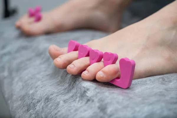 Close-up of womans feet getting pedicure with finger separators.