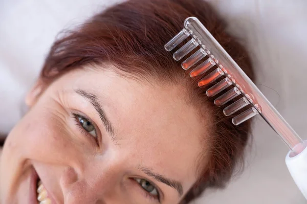 Mujer caucásica en un procedimiento de cuidado del cabello utilizando el aparato Darsonval. — Foto de Stock