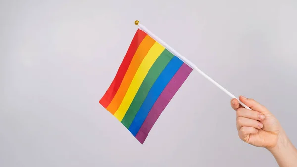 Una mujer sostiene una bandera del arco iris sobre un fondo blanco. —  Fotos de Stock