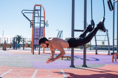 Tişörtsüz adam dışarıda ilmek egzersizi yapıyor.. 