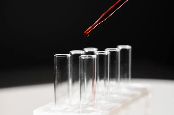 Egy laboratóriumi asszisztens közeli képe, amint a pipettából vért csöpög egy kémcsőbe.. — Stock Fotó