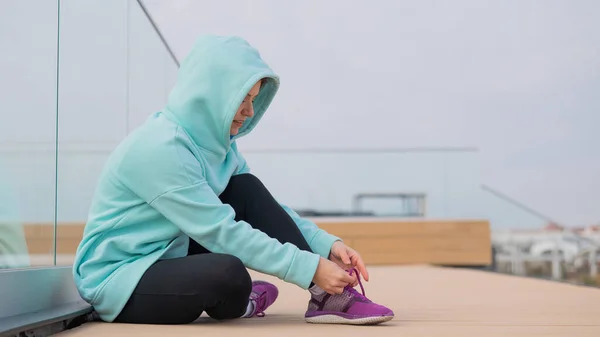 Кавказька жінка в копиці зав'язує шнурки перед тим, як бігати.. — стокове фото