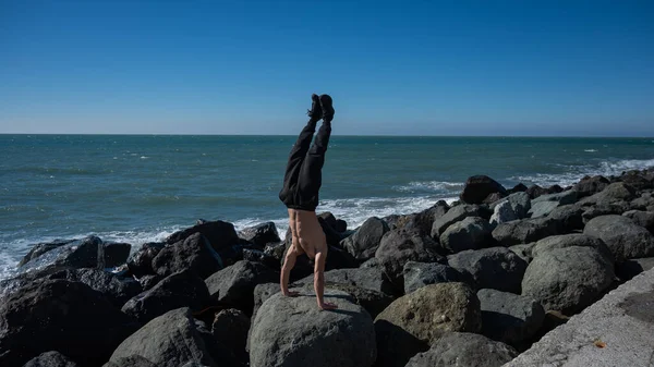 海のそばの岩の上に立つ白人の男. — ストック写真