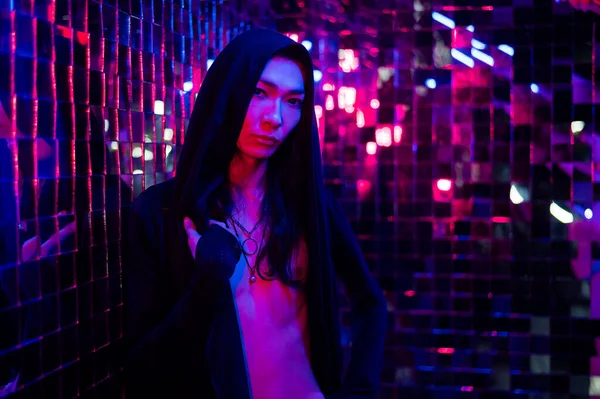 Retrato de close-up de um modelo androgênico em um capô. Masculino transexual em estúdio com luz de néon. — Fotografia de Stock