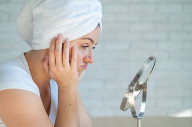 Üzgün bir kadın masada oturur ve aynaya bakar. Hormonal sorunları olan bir kızın düşüklüğü duş aldıktan sonra güzelliğe yol açar. Genç sivilceleri. Kendisi bir dermatolog. Sorunlu cilt.