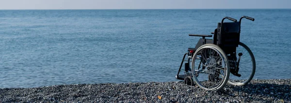 En tom rullstol på en stenig strand. — Stockfoto