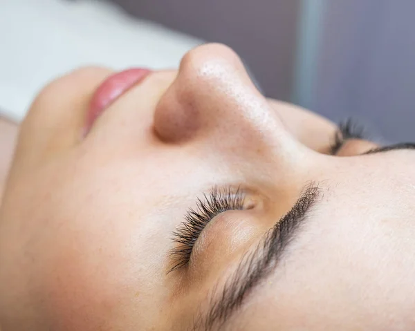 Close-up portrait of a young caucasian woman before eyelash lamination procedure.